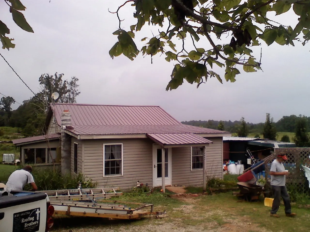 Crew finishing a mauve metal roof on a small farmhouse in Portland